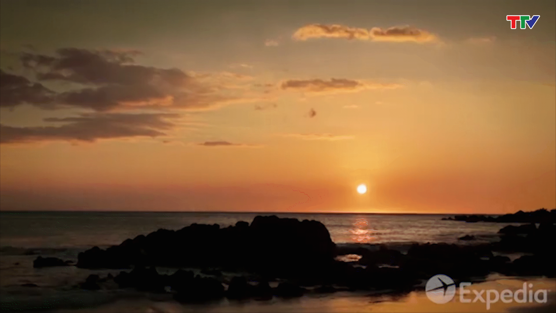 mặt trời lặn ở phía Bắc Thái Bình Dương trông giống như quả bóng lửa đang ngự trị trên bãi biển