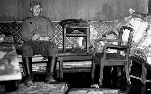 Một chiến sĩ Hồng quân ngồi trên ghế sofa mà gã độc tài Hitler được cho là đã từng ngồi lúc y tự sát. Ảnh: Getty.