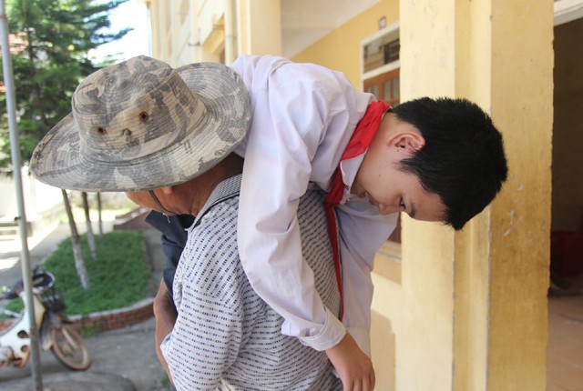 Ông Sơn vác con đưa lên lớp học bởi con trai ông mắc bệnh suy tủy, đôi chân mềm nhũn như bún không thể đứng, xương sống không thể gánh đỡ phần cơ thể phía trên.