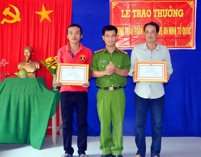 Đại diện Công an huyện Chợ Lách trao giấy khen cho anh Phong và anh Nghĩa.