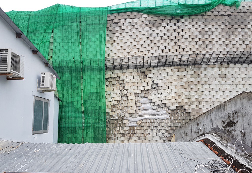 Bê tông, gạch trên bức tường chắn dự án Marina Hill – Đồi Xanh Nha Trang rơi rụng xuống phía nhà dân