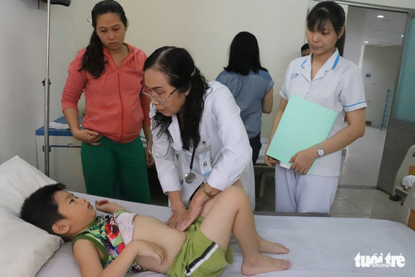 Bác sĩ kiểm tra sức khỏe cho một học sinh lớp 1/5 Trường tiểu học Nguyễn Thị Định, nghi do ngộ độc thực phẩm - Ảnh: XUÂN MAI