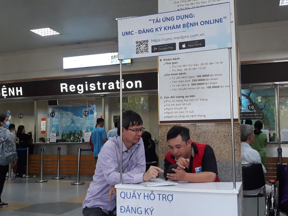 Người dân cài ứng dụng đăng ký khám bệnh online tại Bệnh viện ĐH Y Dược TP.HCM - Ảnh: HOÀNG LỘC