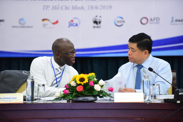 Bộ trưởng Bộ Kế hoạch - đầu tư Nguyễn Chí Dũng trao đổi với ông Ousmane Dione - giám đốc quốc gia của Ngân hàng Thế giới tại Việt Nam - Ảnh: QUANG ĐỊNH
