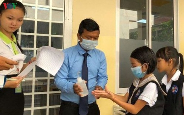 Khử khuẩn cho các em học sinh.
