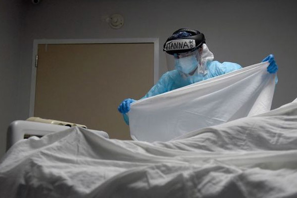 Một nhân viên y tế đang phủ khăn lên thi thể bệnh nhân thiệt mạng vì Covid-19 tại Trung tâm y tế United Memorial ở Houston, Texas, Mỹ. Ảnh: Reuters