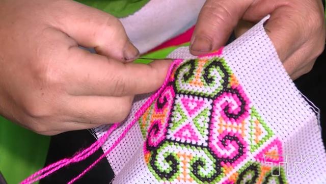 người phụ nữ Mông đang miệt mài, tỉ mẩn thêu những hoa văn, hình khối lên các tấm vải tạo để tạo ra những bộ váy áo đặc sắc của dân tộc mình. 