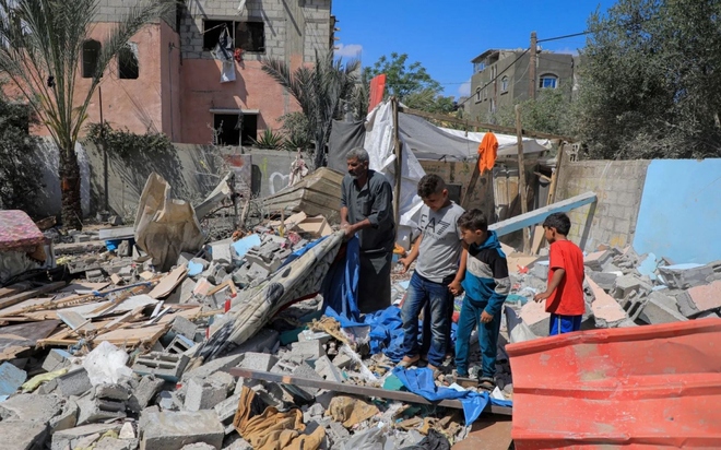 Người dân bên ngôi nhà bị phá hủy ngày 7/5 sau các cuộc tấn công của Israel vào thành phố Rafah, phía nam Dải Gaza. Ảnh: Tân Hoa xã
